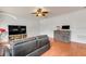 Comfortable living room with wood floors, a leather couch, a ceiling fan, and a large television at 4445 Blue Major Dr, Windermere, FL 34786