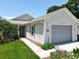 Well-maintained home with light gray siding, a palm tree, a two-car garage, and a manicured lawn at 4521 Eaglewood Dr, Leesburg, FL 34748