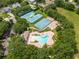 An aerial view of a community pool, basketball court, tennis courts and playground nestled amongst lush trees at 4548 Barrister Dr, Clermont, FL 34711