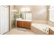 Well-lit bathroom features a shower, soaking tub, and vanity with wooden cabinets at 4548 Barrister Dr, Clermont, FL 34711