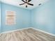 Light blue bedroom with a ceiling fan, window, and neutral-toned wood floors at 4548 Barrister Dr, Clermont, FL 34711