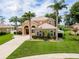 Beautiful two-story stucco home features manicured lawn, decorative shrubs, and mature palm trees in a tropical landscape at 4548 Barrister Dr, Clermont, FL 34711