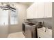 A well-lit laundry room featuring a washer, dryer, sink, and storage cabinets at 4548 Barrister Dr, Clermont, FL 34711