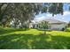 Expansive backyard featuring a lush lawn, mature trees, and outdoor seating area at 4904 Long Meadow Dr, Leesburg, FL 34748