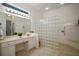 Bathroom featuring a vanity with sink, large mirror, tiled floor, and a glass block shower at 4904 Long Meadow Dr, Leesburg, FL 34748