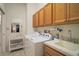 Bright laundry room features wood cabinets, washing machine, and sink with cleaning supplies at 4904 Long Meadow Dr, Leesburg, FL 34748
