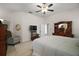 Comfortable main bedroom featuring large bed, tiled floor, ceiling fan, recliner and ensuite bathroom at 4904 Long Meadow Dr, Leesburg, FL 34748