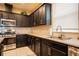 Well-lit kitchen featuring dark cabinets, stainless steel appliances, and light granite countertops at 525 Narrow View Ln, Groveland, FL 34736
