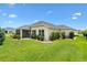 Well-maintained backyard featuring lush green grass, manicured shrubbery, and an enclosed lanai at 5311 Eads Ter, The Villages, FL 32163