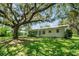 Back exterior view of the house shows a large yard with shade from large trees at 5319 Eagles Nest Rd, Fruitland Park, FL 34731