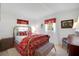 Comfortable bedroom features a gold bed frame and red floral patterned bedding at 5319 Eagles Nest Rd, Fruitland Park, FL 34731