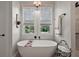 This is a pristine bathroom with an elegant stand-alone tub under two windows with woven shades at 622 W 11Th Ave, Mount Dora, FL 32757