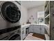 Bright and modern laundry room with grey cabinets, open shelving, and a window overlooking the exterior at 622 W 11Th Ave, Mount Dora, FL 32757