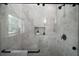 Modern walk-in shower featuring gray tiling, glass doors, black hardware, and a built-in shelf at 622 W 11Th Ave, Mount Dora, FL 32757
