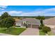 Home featuring a three-car garage, neutral color scheme, and mature landscaping at 9413 Ivywood St, Clermont, FL 34711