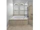 Bathroom featuring a soaking tub next to a glass shower with tiled surround and two windows at 9413 Ivywood St, Clermont, FL 34711