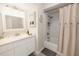 Bright bathroom with a white vanity, decorative mirror, and shower with a neutral-toned curtain at 999 W Juniata St, Clermont, FL 34711