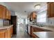 Open kitchen with wood cabinets, bright counters, and stainless-steel appliances, leading to eat-in kitchen at 11926 Milan Way, Leesburg, FL 34788