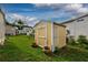 Yellow and white shed with lattice detail on green lawn, enhanced by potted plants at 11926 Milan Way, Leesburg, FL 34788