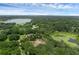 Expansive aerial view of a lakeside estate surrounded by lush landscaping, mature trees, and tranquil waters at 1325 Otters View Ct, Fruitland Park, FL 34731
