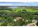 Aerial view of the property, showcasing a pool, surrounding woods, lake, and expansive green space at 1325 Otters View Ct, Fruitland Park, FL 34731