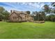 A lush backyard with a well-maintained lawn and mature trees surrounds a brick home at 1325 Otters View Ct, Fruitland Park, FL 34731