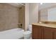 Bathroom featuring tiled shower-tub, tan walls, and a brown vanity with granite countertops at 1325 Otters View Ct, Fruitland Park, FL 34731
