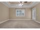 Carpeted bedroom with tray ceiling, fan, window, and door to screened patio at 1325 Otters View Ct, Fruitland Park, FL 34731