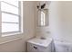 Small bathroom features a toilet, a sink and vanity, a mirror, and a bright window at 1415 Braebury Dr, Leesburg, FL 34748