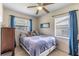 Cozy bedroom with a comfortable queen-size bed, plush carpeting, blue curtains, and windows offering natural light at 1415 Braebury Dr, Leesburg, FL 34748