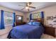 Comfortable bedroom with a queen-size bed with matching blue bedding, ceiling fan, and natural light from the windows at 1415 Braebury Dr, Leesburg, FL 34748