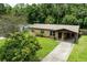 Inviting home featuring covered parking, mature landscaping, and a well-manicured lawn at 1415 Braebury Dr, Leesburg, FL 34748