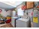 Functional laundry room features a washer, dryer, water heater, storage shelves, and white-painted cinder block walls at 1415 Braebury Dr, Leesburg, FL 34748
