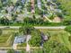 This aerial view showcases homes in a suburban neighborhood with mature trees, manicured lawns, and private pools at 1511 W Magnolia St, Clermont, FL 34711