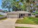 Charming single-story home with lush front lawn, mature trees, and a two-car garage at 1511 W Magnolia St, Clermont, FL 34711