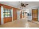 Spacious living room features wood paneling, a ceiling fan, and bright natural light from a large window at 16318, 16250 & 16300 County Road 448, Mount Dora, FL 32757