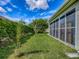 A serene backyard featuring a screened-in lanai, lush lawn, privacy hedges, and a charming birdhouse at 1675 Westminster Ct, The Villages, FL 32162