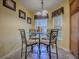 Breakfast nook with a glass-top table and four chairs, illuminated by a chandelier and windows at 1675 Westminster Ct, The Villages, FL 32162