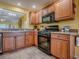 Kitchen featuring wood cabinets and black appliances with a view to the open concept living area at 1675 Westminster Ct, The Villages, FL 32162