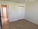 Cozy bedroom with tile flooring, a double-door closet, and access to the hallway at 17483 Se 74Th Netherclift Ter, The Villages, FL 32162