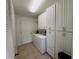 Bright laundry room with washer, dryer, and built-in storage cabinets at 17483 Se 74Th Netherclift Ter, The Villages, FL 32162