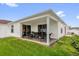 A view of a covered backyard patio with comfortable seating and lush green grass surrounding it at 17695 Se 84Th Peyton Ct, The Villages, FL 32162