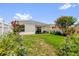 A spacious backyard featuring a covered patio, lush lawn, and colorful landscaping at 17695 Se 84Th Peyton Ct, The Villages, FL 32162