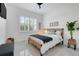 Bright bedroom featuring a woven-frame bed, plantation shutters, and neutral decor at 1990 Wallingford Loop, Mount Dora, FL 32757