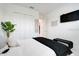 Modern bedroom with a flat-screen TV, white bedding, and minimalist decor at 1990 Wallingford Loop, Mount Dora, FL 32757