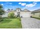 Charming single-story home featuring manicured lawn, brick driveway, and a welcoming front entrance at 1990 Wallingford Loop, Mount Dora, FL 32757