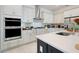 Modern kitchen with stainless steel appliances, white cabinets, and a large island with white countertops at 1990 Wallingford Loop, Mount Dora, FL 32757