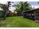 Spacious backyard with a grassy area, mature trees, and a screened-in patio at 212 Blossom Ln, Winter Park, FL 32789