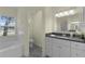 Bright bathroom with a combination tub/shower, white vanity, and a large window overlooking the yard at 24954 Navel Ave, Leesburg, FL 34748