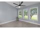 Bright bedroom featuring gray walls, laminate flooring, a ceiling fan, and scenic window views at 24954 Navel Ave, Leesburg, FL 34748